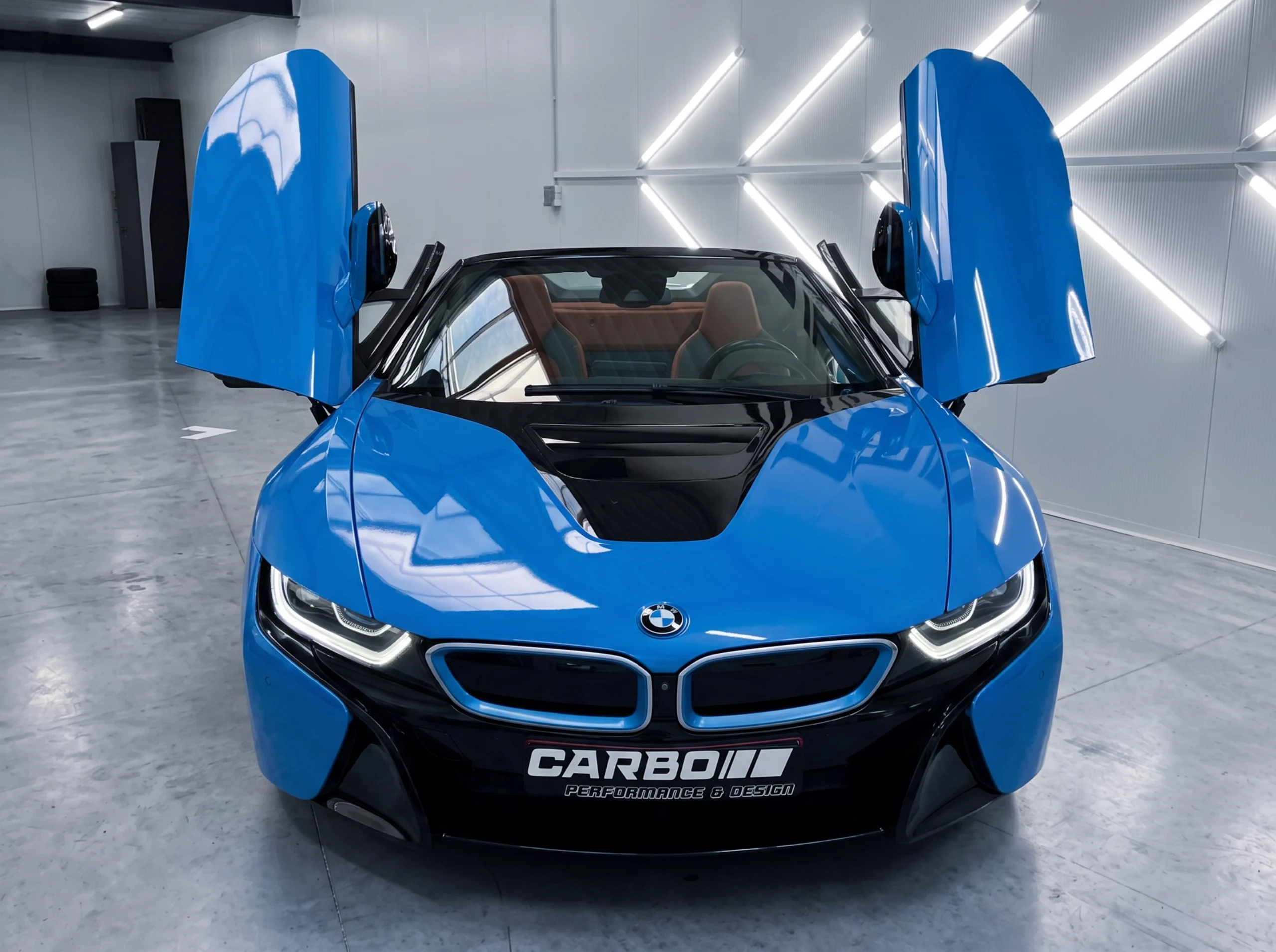 Carbo-Portofilo 8 BMW i8 Roadster met geopende vlugeldeuren volledig gewrapt in Gloss Intense Blue in de detailing studio