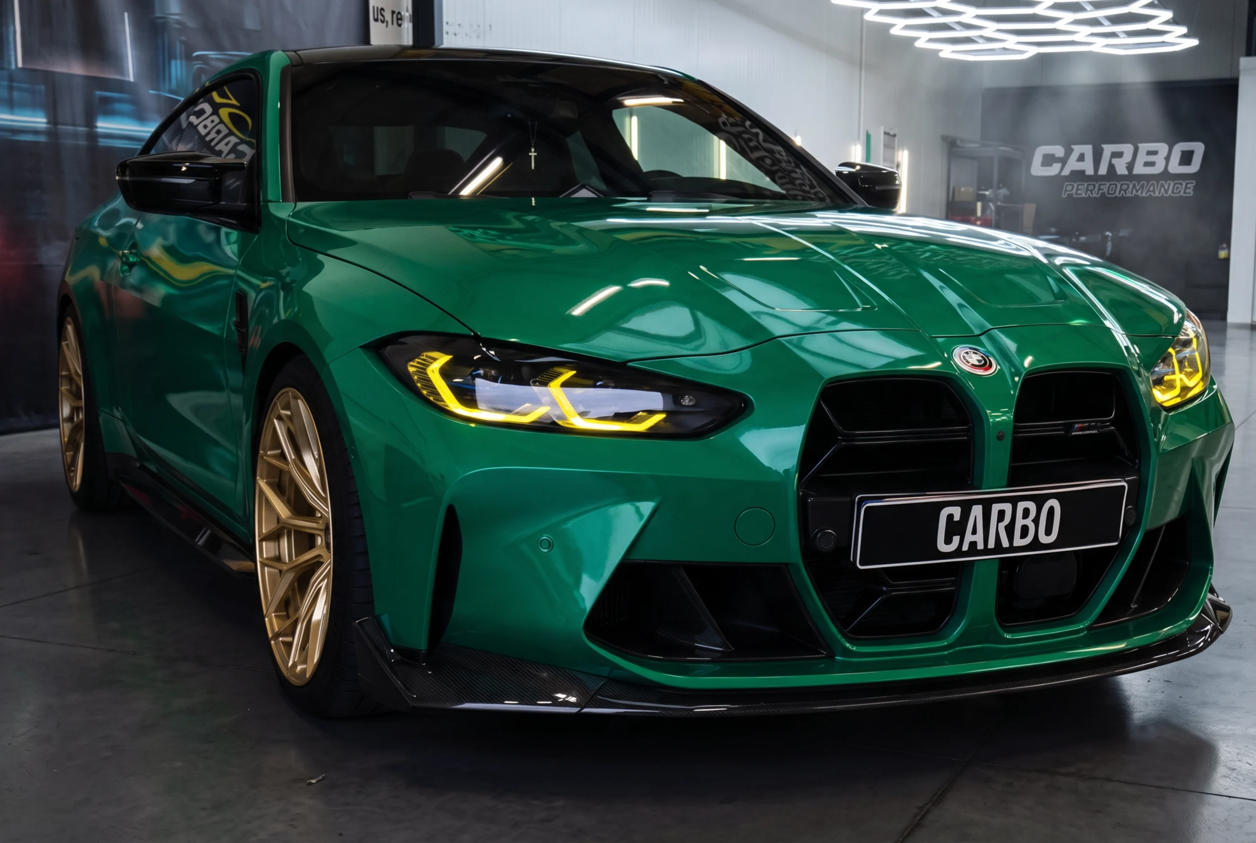 Groene BMW M4 Competition G82 met kleurswitch wrap, goudkleurige velgen en gele CSL-stijl DRL-verlichting