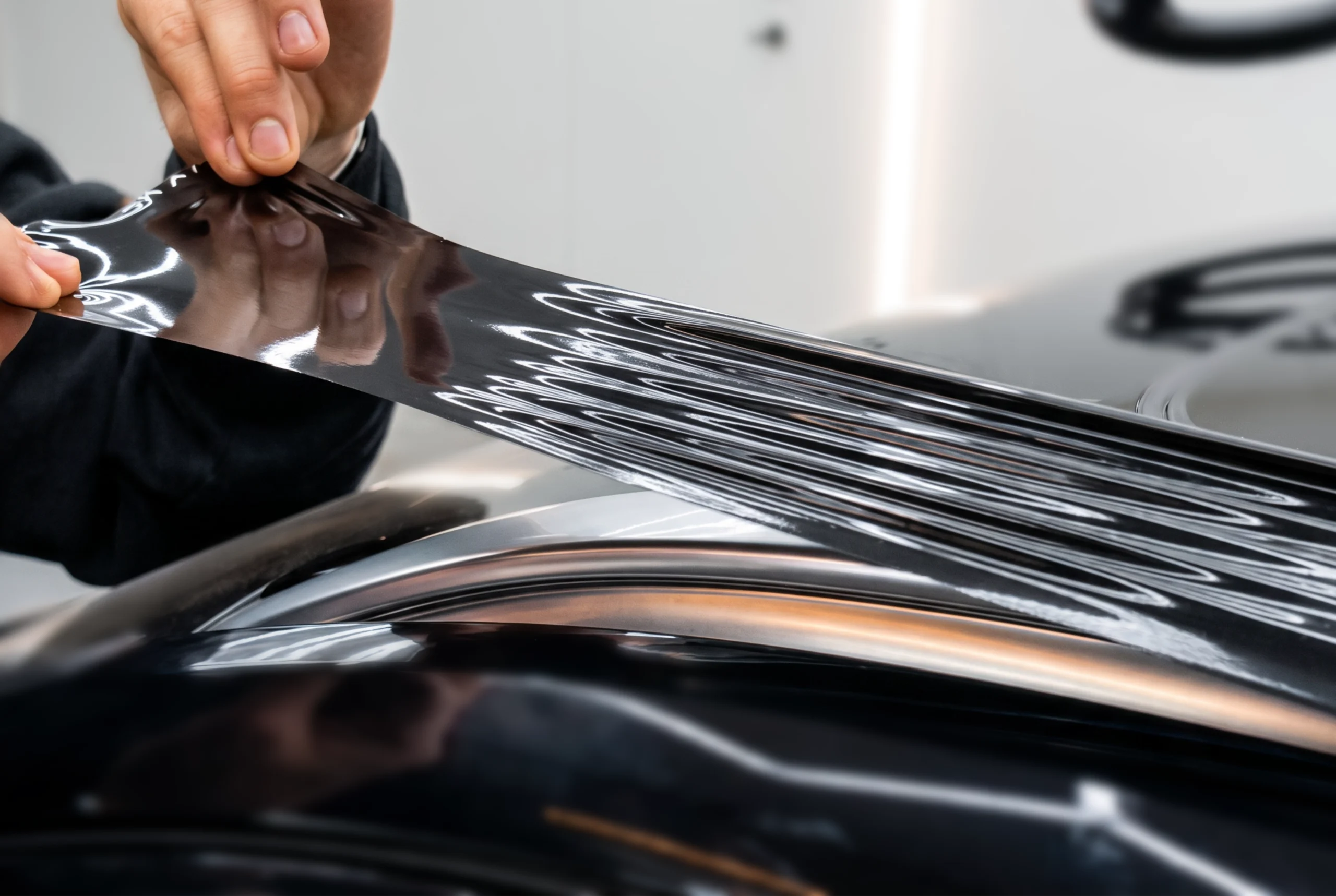 Professionele Chrome Delete installatie: hoogglans zwarte wrap folie wordt nauwkeurig aangebracht op een chroom dakrail