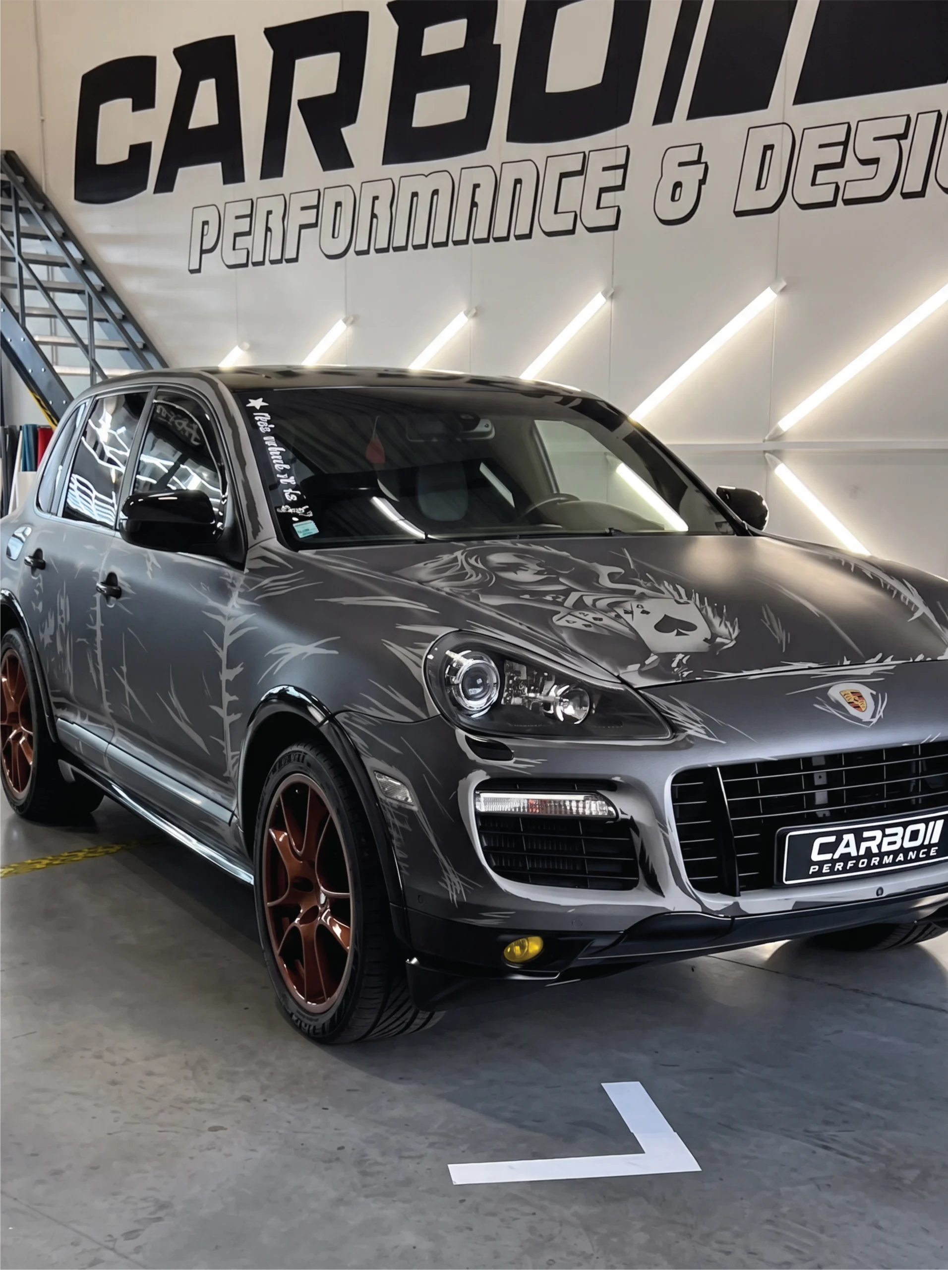 Carbo-Portofilo 21 Gepersonaliseerde Porsche Cayenne GTS met custom design wrap, glanzend zwarte accenten en koperkleurige velgen in de studio