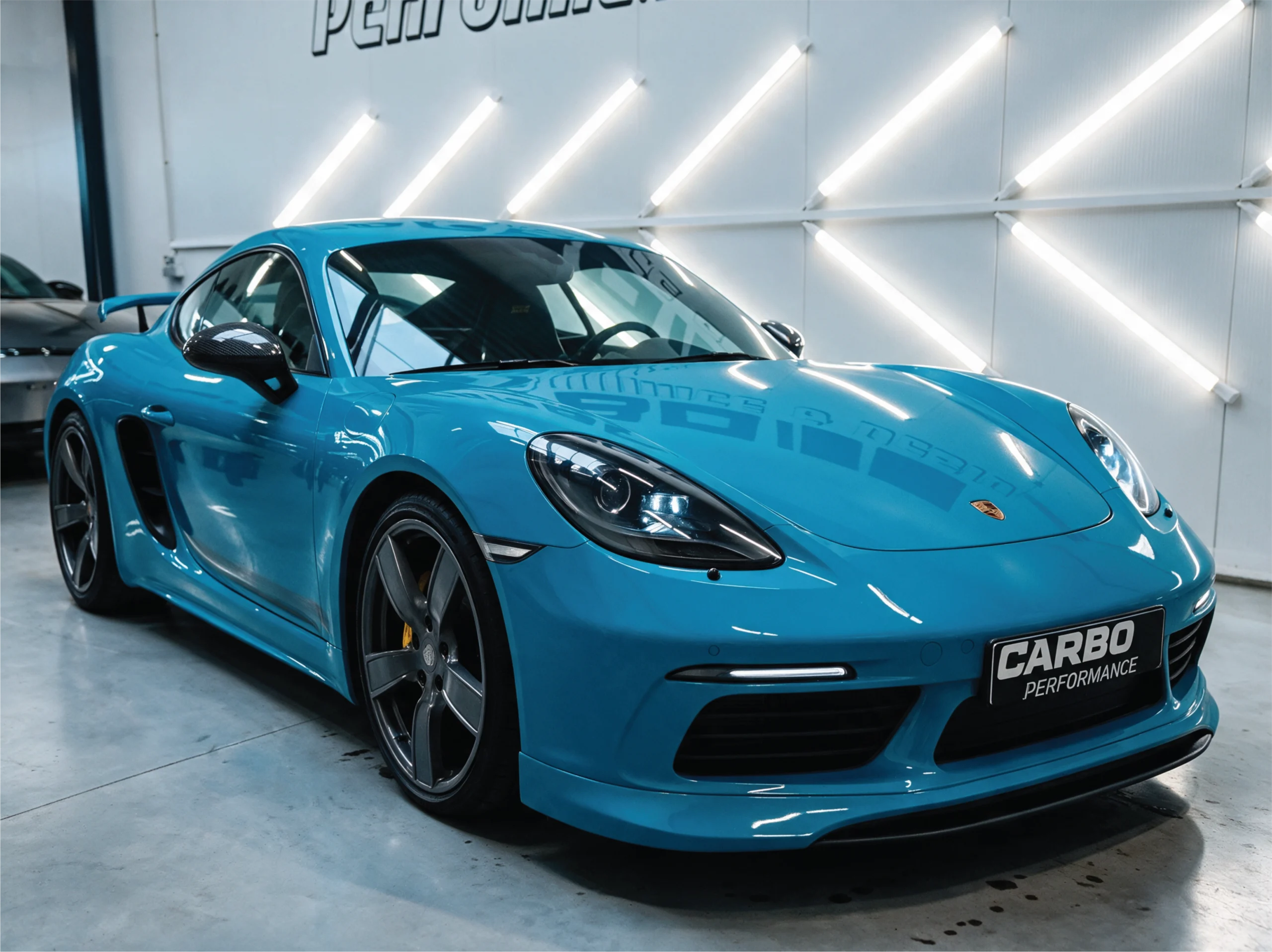 Carbo-Portofilo 11 Blauwe Porsche 718 Cayman T met opvallende gele remklauwen achter lichtmetalen velgen in de studio